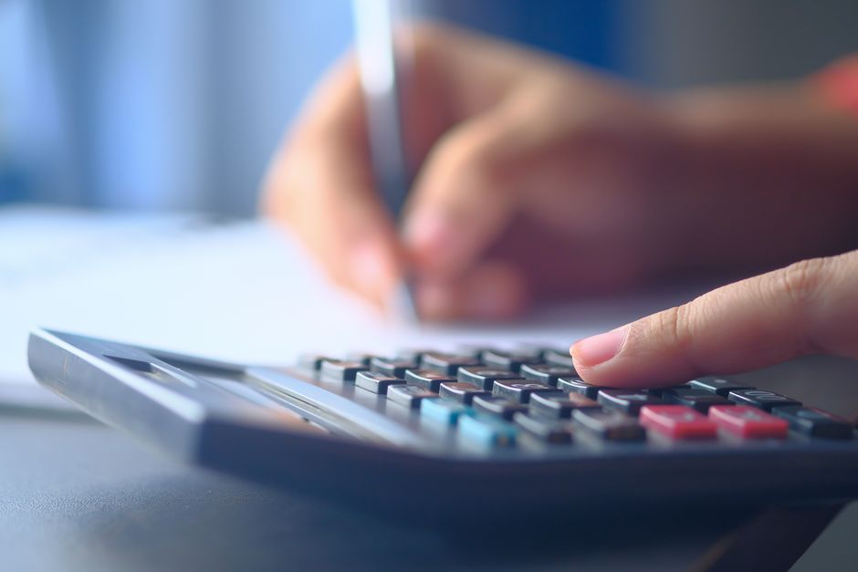 Gros plan sur des mains utilisant une calculatrice et écrivant, illustrant la gestion budgétaire et la planification financière.