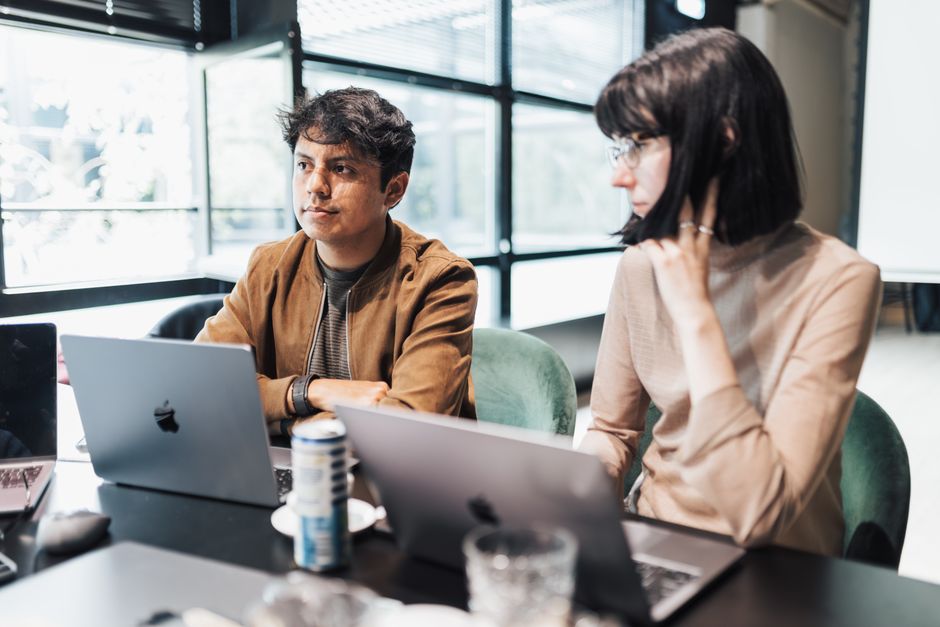 De jeunes professionnels collaborent sur des ordinateurs portables dans un espace de bureau lumineux et moderne.