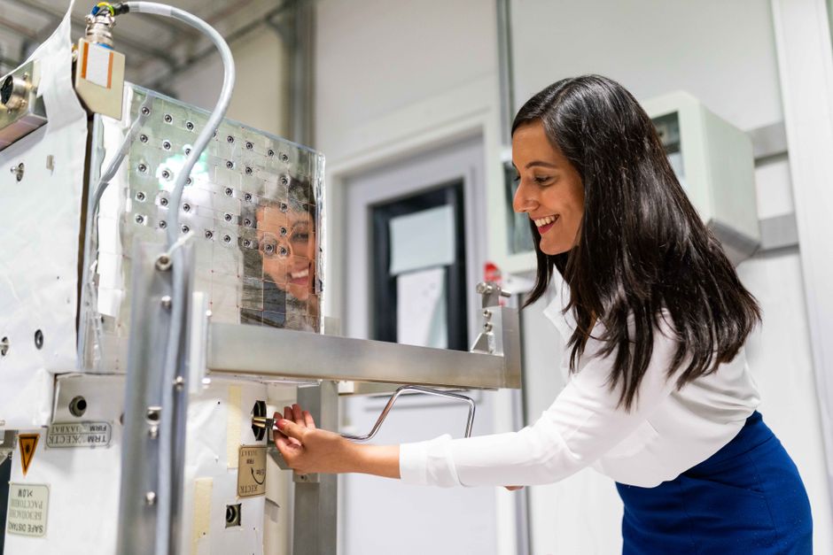 Ingénieure utilisant une machine dans un laboratoire avec une surface réfléchissante.