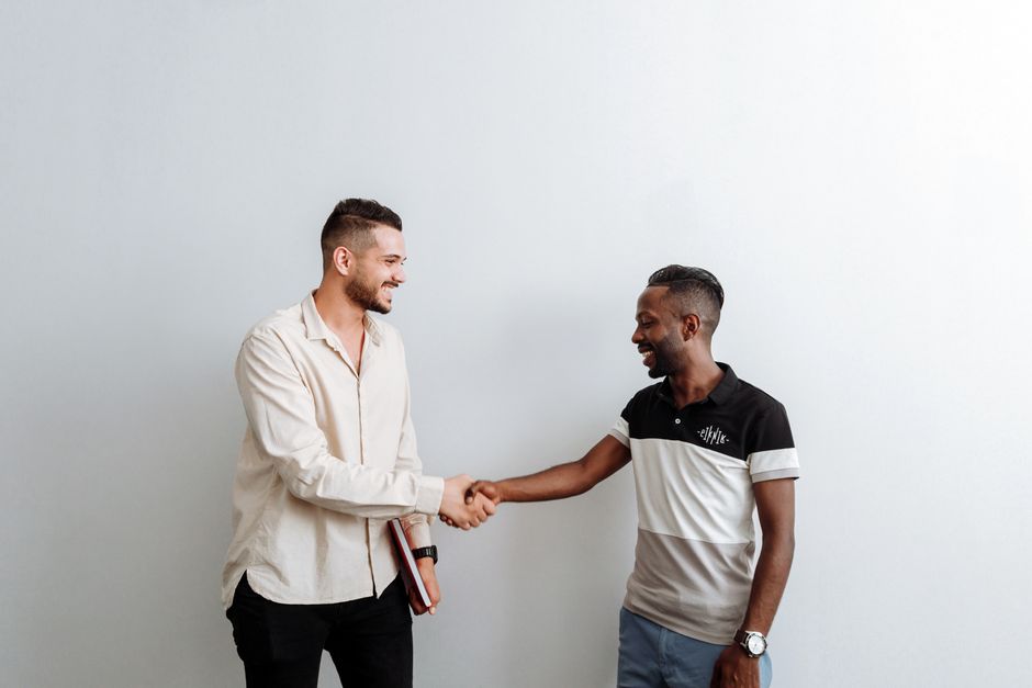 Deux professionnels souriants concluent un accord commercial en se serrant la main en intérieur.