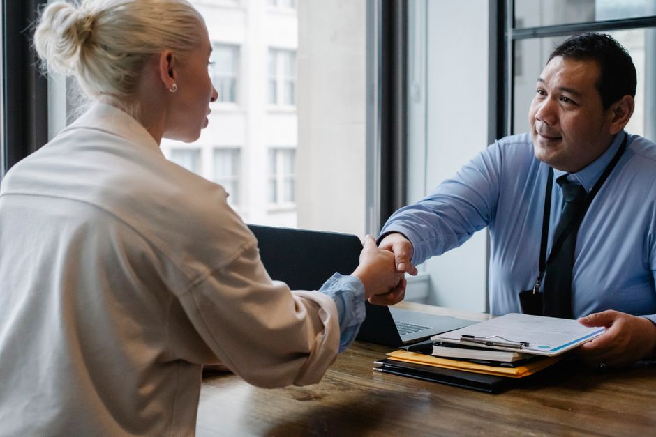 Un entrepreneur masculin et une candidate se serrant la main lors d'un entretien d'embauche dans une entreprise.