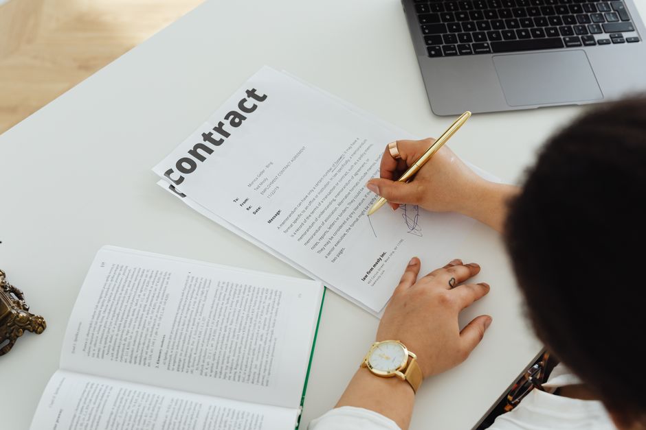 Professional signing a business contract at a modern desk setup for office work.