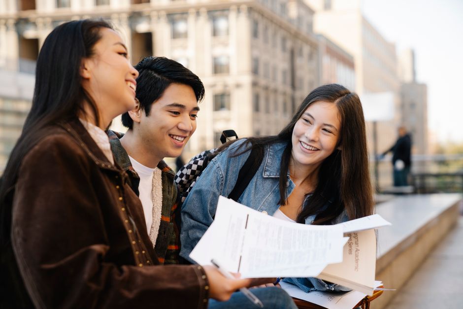 Three young adults sitting on campus benches, enjoying their conversation.