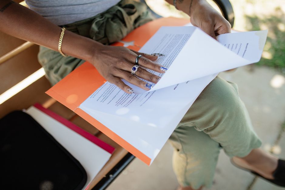 Gros plan sur une femme consultant des documents sur un banc à la lumière naturelle.