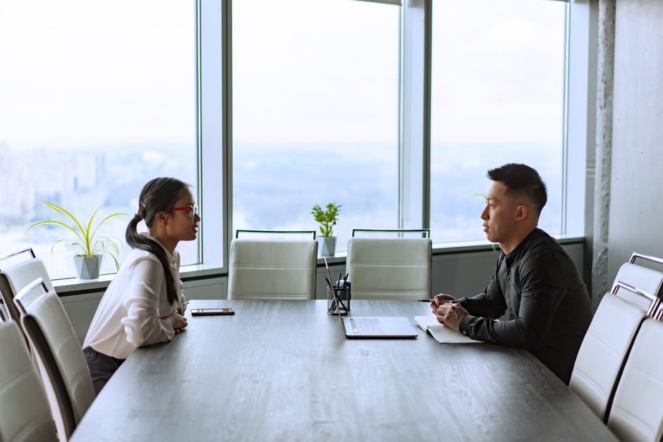 Two professionals engaged in a business meeting in a modern office with city views.
