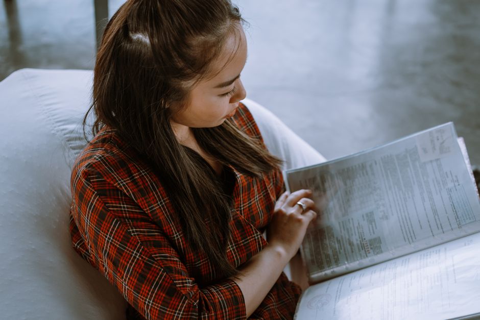 Une femme assise à l'intérieur passe en revue des documents importants, en se concentrant sur la budgétisation et la comptabilité.